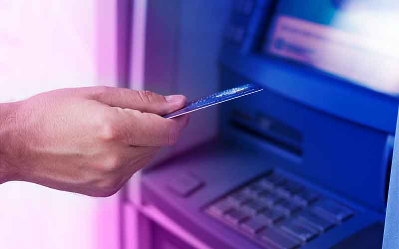 Nahaufnahme einer Hand mit Bankkarte vor einem Geldautomaten – Symbolbild für Gehaltsauszahlung