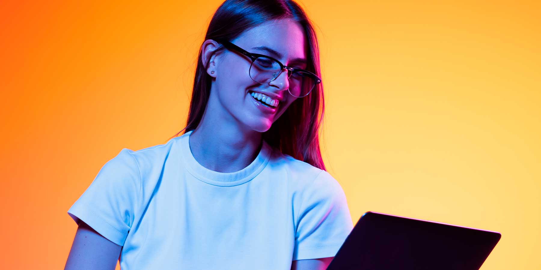 Junge Frau mit Brille und Laptop vor orangem Hintergrund – Einstiegsmöglichkeiten für Berufseinsteiger bei Printus