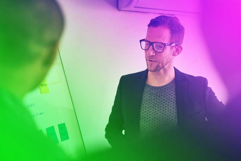 Mitarbeiter von Printus erklärt am Whiteboard eine Idee – Szene aus einem Meeting mit Corporate-Influencer-Charakter