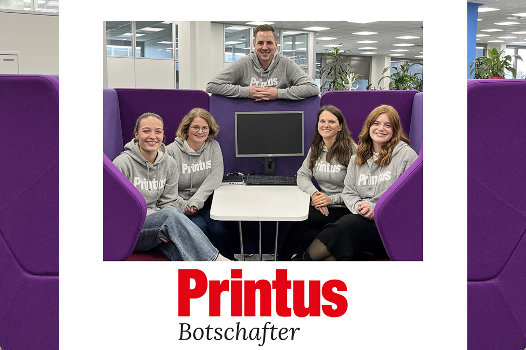 Fünf Mitarbeitende von Printus im Markenbotschafter-Hoodie, sitzend in moderner Büroumgebung – Gruppenbild mit Teamgeist