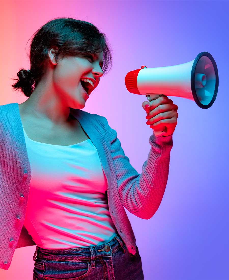 Junge Frau mit Megafon, energetisch und entschlossen, vor buntem Hintergrund – steht für Selbstbewusstsein, Engagement und Zukunftschancen bei Printus