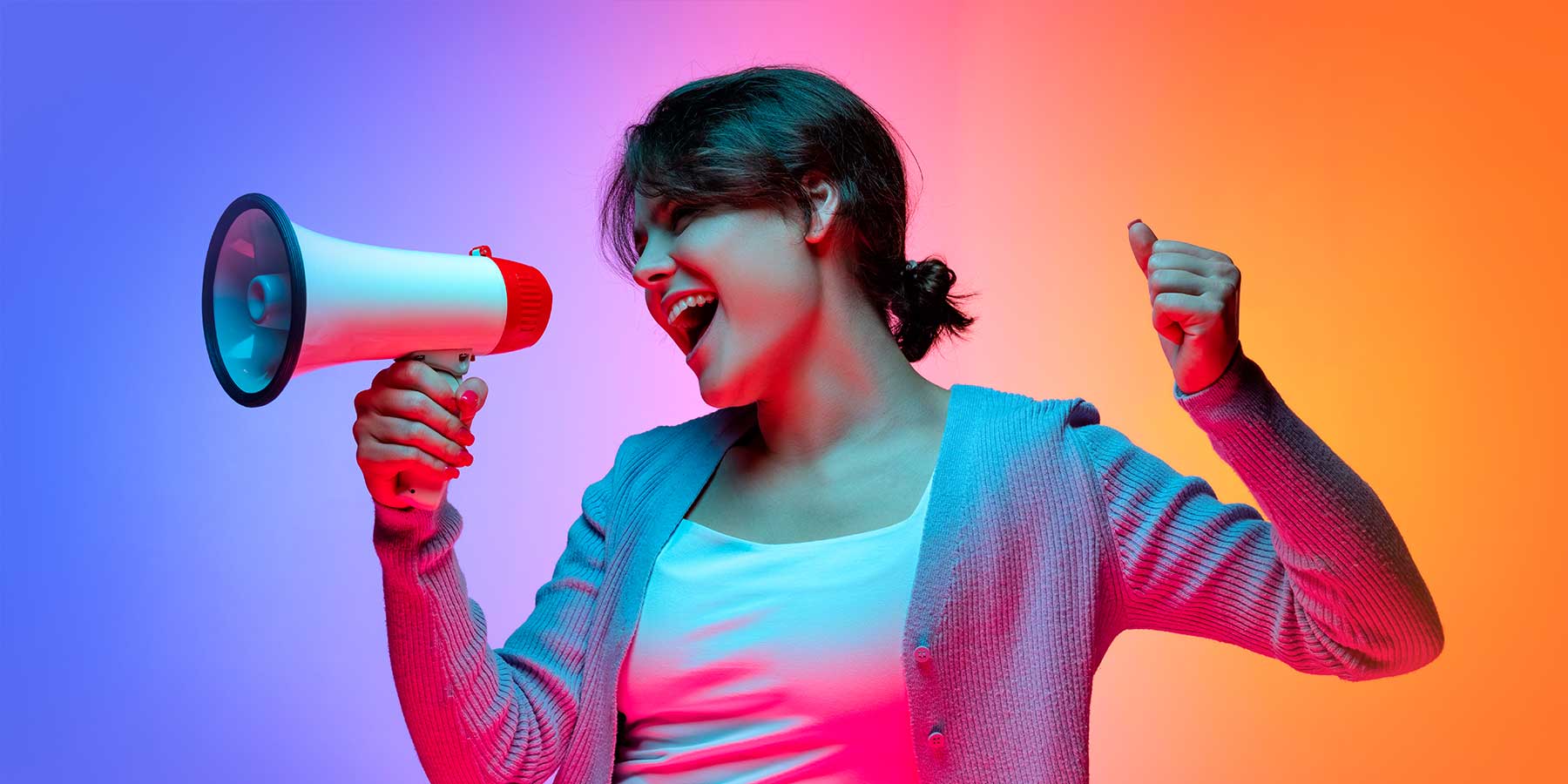 Junge Frau mit Megafon, energetisch und entschlossen, vor buntem Hintergrund – steht für Selbstbewusstsein, Engagement und Zukunftschancen bei Printus